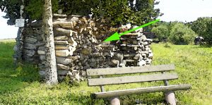 Foto Bank mit Holzstapel dahinter und Pfeil für Schatzsuche